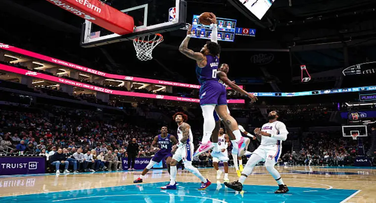 Charlotte Hornets forward Miles Bridges performing a powerful one-handed dunk over Philadelphia 76ers defenders during their January 26, 2026 matchup at Spectrum Center.