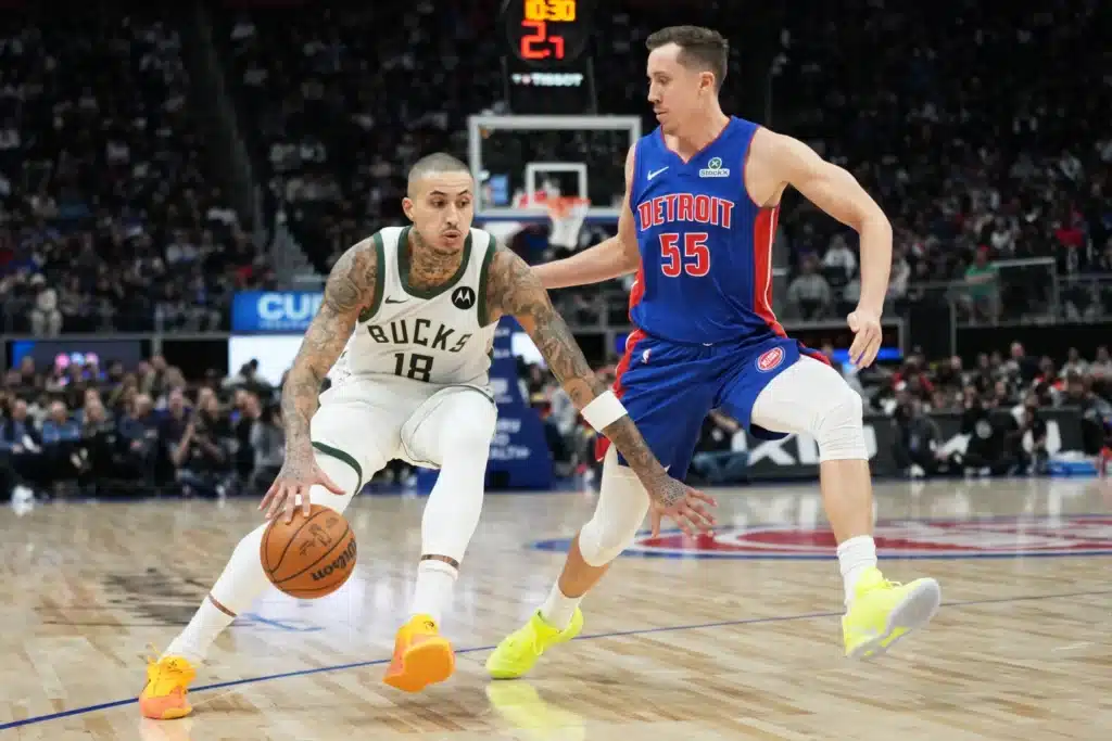 Milwaukee Bucks player dribbling the ball while Detroit Pistons defender guards him during an NBA game