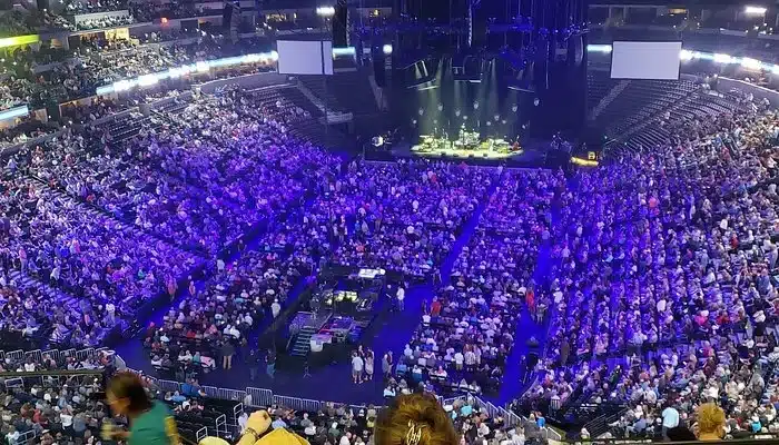 
Inside Ball Arena Denver during a live concert showing a packed crowd, purple stage lighting, and large video screens