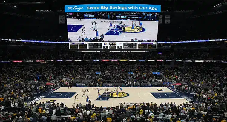 Wide-angle interior view of Gainbridge Fieldhouse in Indianapolis packed with fans during an Indiana Pacers home game with the large center scoreboard lit up