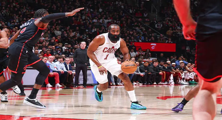 James Harden wearing Cleveland Cavaliers jersey number 1 dribbles the ball under pressure from Toronto Raptors defenders during Game 3 of the 2026 NBA Playoffs