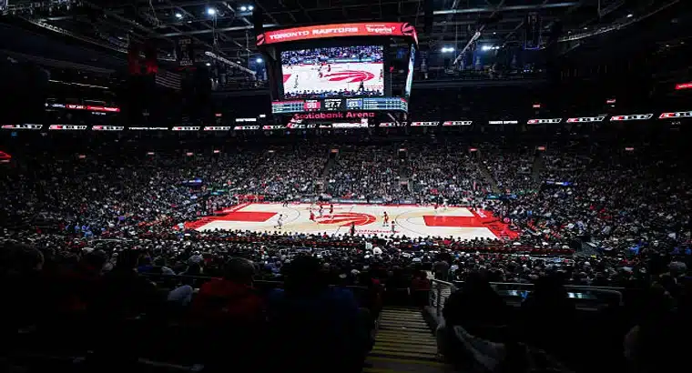 Inside Scotiabank Arena during a Toronto Raptors NBA game, showing the full lower bowl crowd, NBA court, and the massive center-hung scoreboard